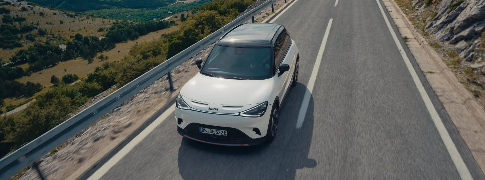 Auto eléctrico smart #1 color blanco siendo conducido por carretera. 